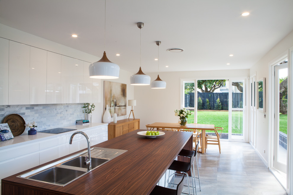 Idéer för ett stort modernt kök, med en dubbel diskho, luckor med upphöjd panel, vita skåp, laminatbänkskiva, grått stänkskydd, stänkskydd i stenkakel, vita vitvaror, en köksö och grått golv