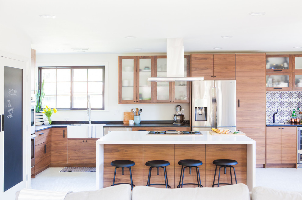 Small midcentury l-shaped open plan kitchen in San Francisco with a belfast sink, flat-panel cabinets, medium wood cabinets, multi-coloured splashback, ceramic splashback, stainless steel appliances, porcelain flooring, an island, white floors and soapstone worktops.