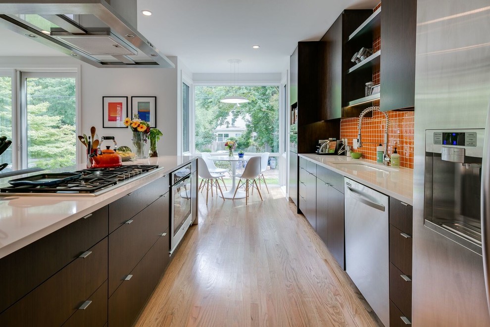 Inspiration for a contemporary galley kitchen/diner in DC Metro with a submerged sink, flat-panel cabinets, dark wood cabinets, orange splashback, stainless steel appliances, light hardwood flooring, an island and beige floors.