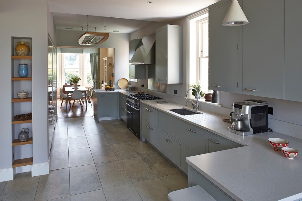 This is an example of a medium sized modern galley kitchen/diner in Surrey with a single-bowl sink, flat-panel cabinets, grey cabinets, stainless steel appliances and no island.