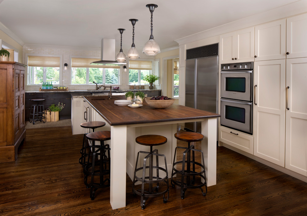 Diseño de cocina rústica con puertas de armario blancas, electrodomésticos de acero inoxidable, suelo de madera en tonos medios y una isla