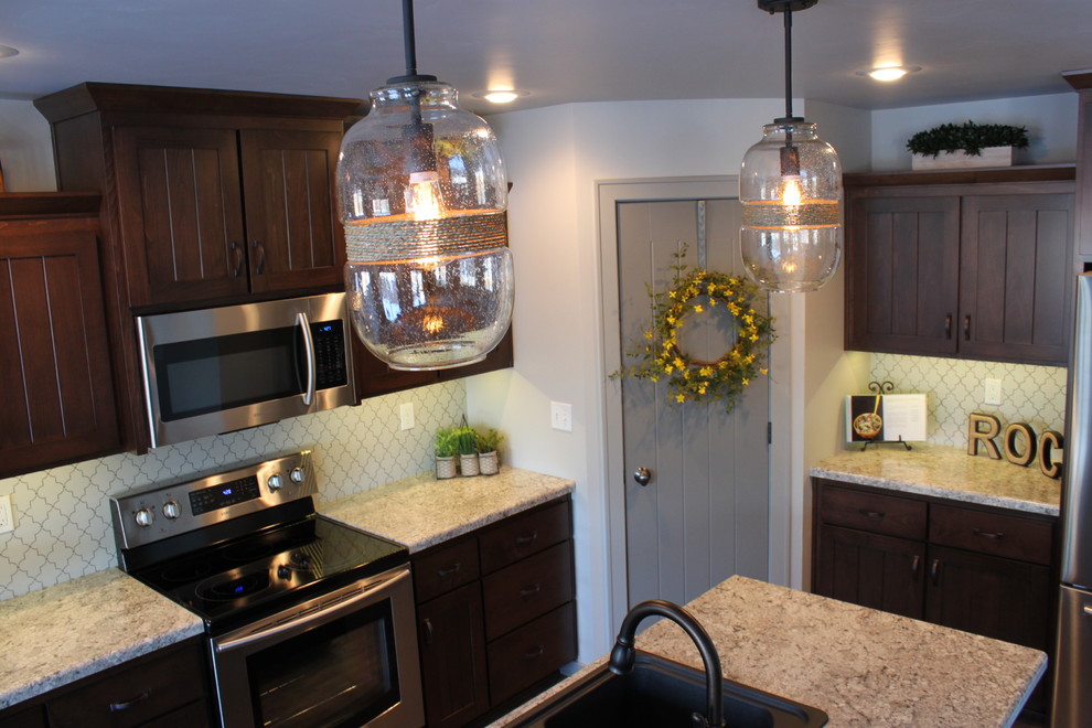 Foto di una cucina stile americano di medie dimensioni con lavello da incasso, ante lisce, ante in legno scuro, top in laminato, paraspruzzi grigio e elettrodomestici in acciaio inossidabile
