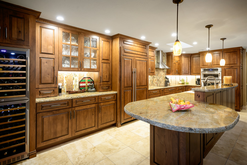 Inspiration for a mid-sized rustic l-shaped travertine floor open concept kitchen remodel in Phoenix with a drop-in sink, raised-panel cabinets, medium tone wood cabinets, granite countertops, green backsplash, mosaic tile backsplash, paneled appliances and an island