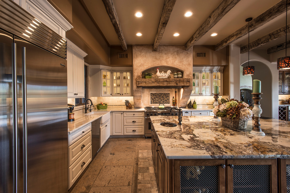 Inspiration for a large rustic l-shaped travertine floor open concept kitchen remodel in Phoenix with a farmhouse sink, raised-panel cabinets, white cabinets, granite countertops, beige backsplash, stone tile backsplash, stainless steel appliances and an island