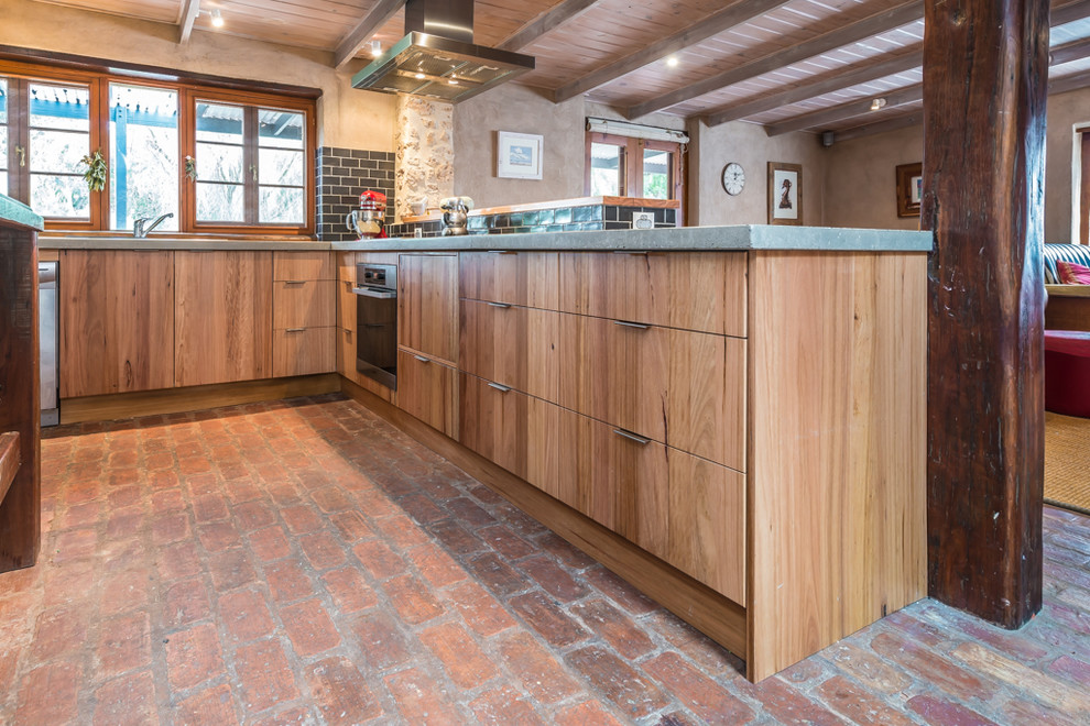 Foto på ett mellanstort rustikt kök, med en dubbel diskho, släta luckor, skåp i mellenmörkt trä, bänkskiva i betong, svart stänkskydd, stänkskydd i tunnelbanekakel, rostfria vitvaror, tegelgolv och en köksö