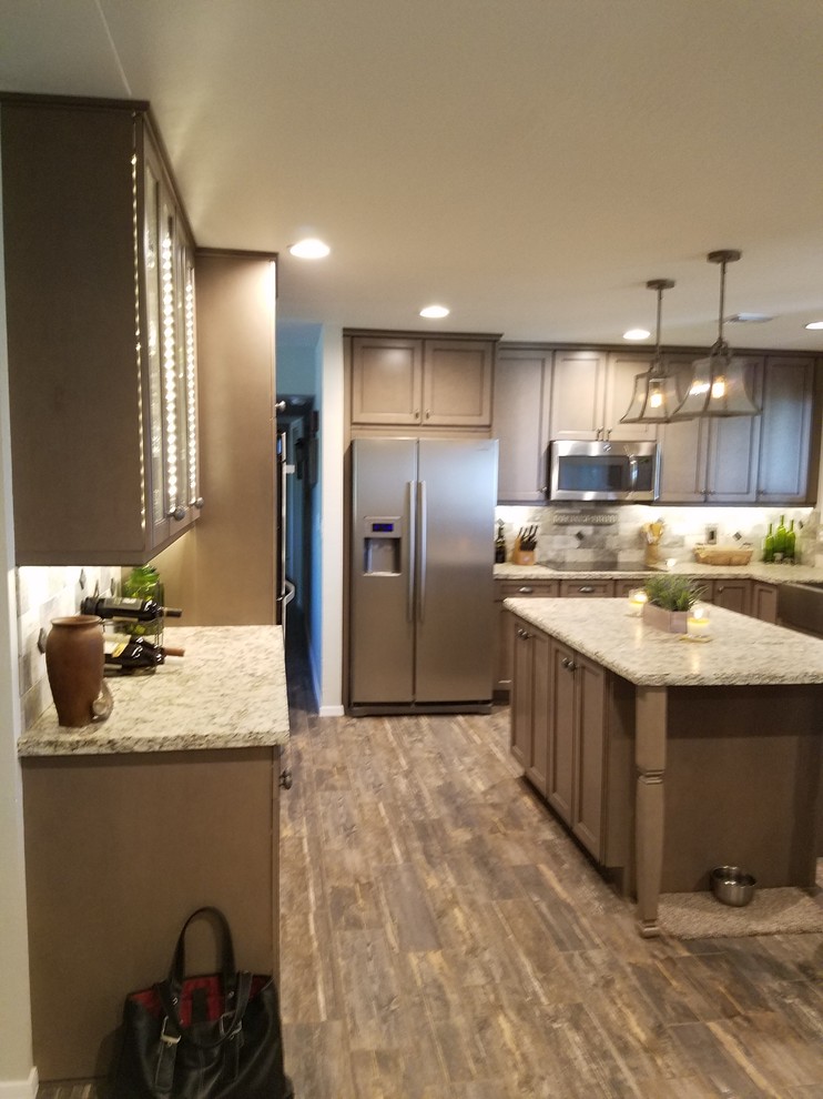 Mid-sized farmhouse u-shaped porcelain tile eat-in kitchen photo in Phoenix with a farmhouse sink, flat-panel cabinets, brown cabinets, granite countertops, gray backsplash, stone tile backsplash, stainless steel appliances and an island