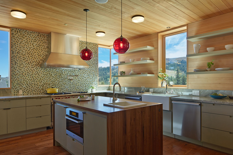 This is an example of an expansive rustic l-shaped kitchen in San Francisco with a belfast sink, flat-panel cabinets, grey cabinets, mosaic tiled splashback, stainless steel appliances and medium hardwood flooring.