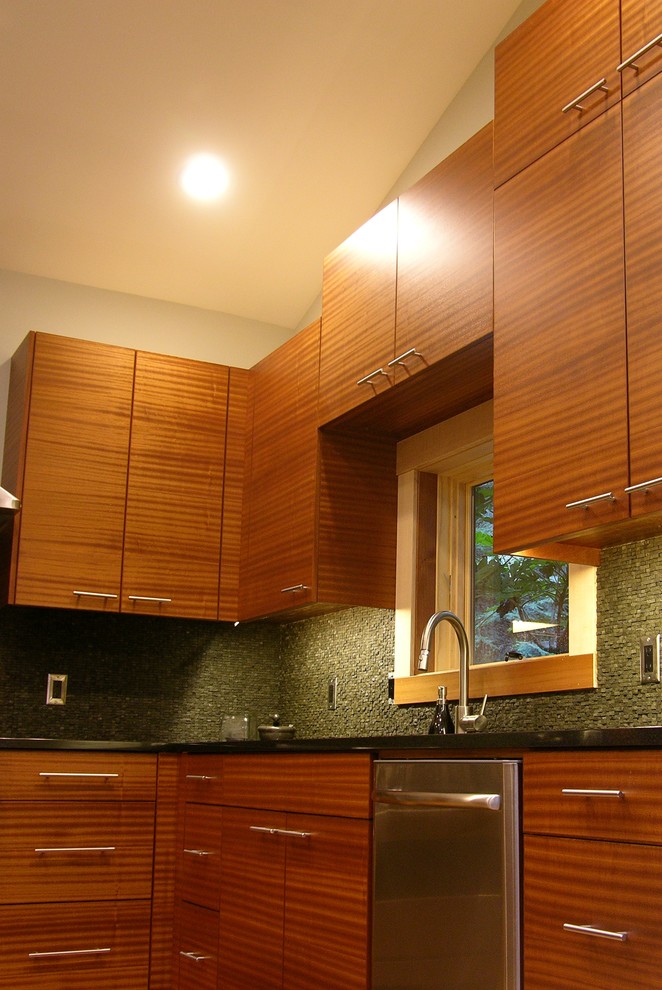Idéer för funkis kök, med en integrerad diskho, släta luckor, skåp i mellenmörkt trä, granitbänkskiva, grått stänkskydd, stänkskydd i stenkakel och rostfria vitvaror