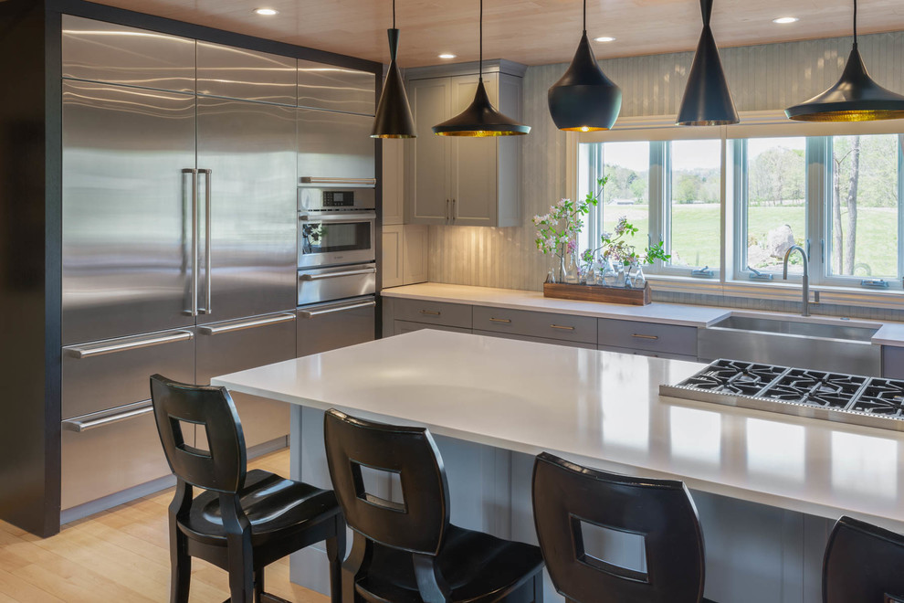 Eat-in kitchen - large modern l-shaped light wood floor and brown floor eat-in kitchen idea in Other with a farmhouse sink, recessed-panel cabinets, stainless steel countertops, stainless steel appliances, two islands, gray countertops, gray cabinets and gray backsplash
