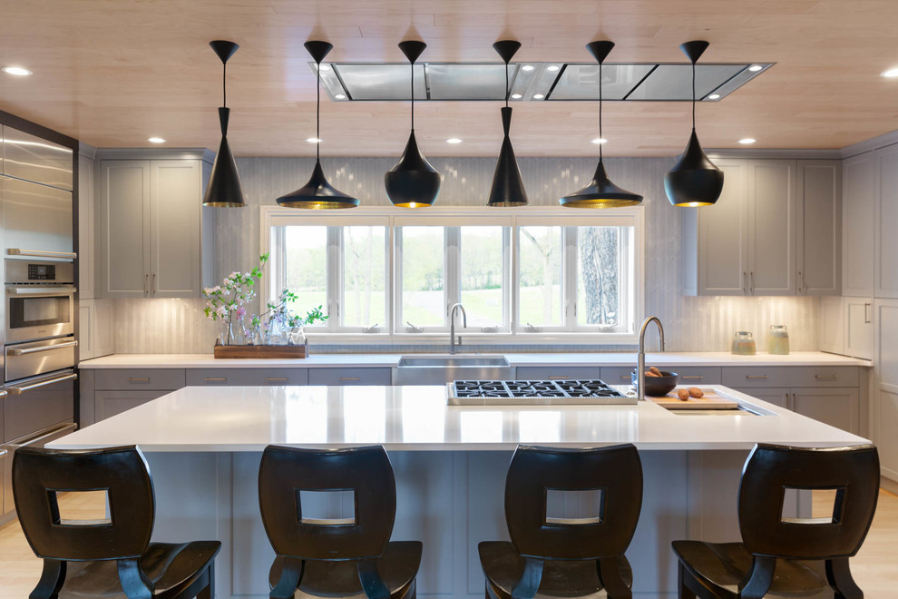 Large minimalist l-shaped light wood floor and brown floor eat-in kitchen photo in Other with a farmhouse sink, recessed-panel cabinets, stainless steel countertops, stainless steel appliances, two islands, gray countertops, gray cabinets and gray backsplash