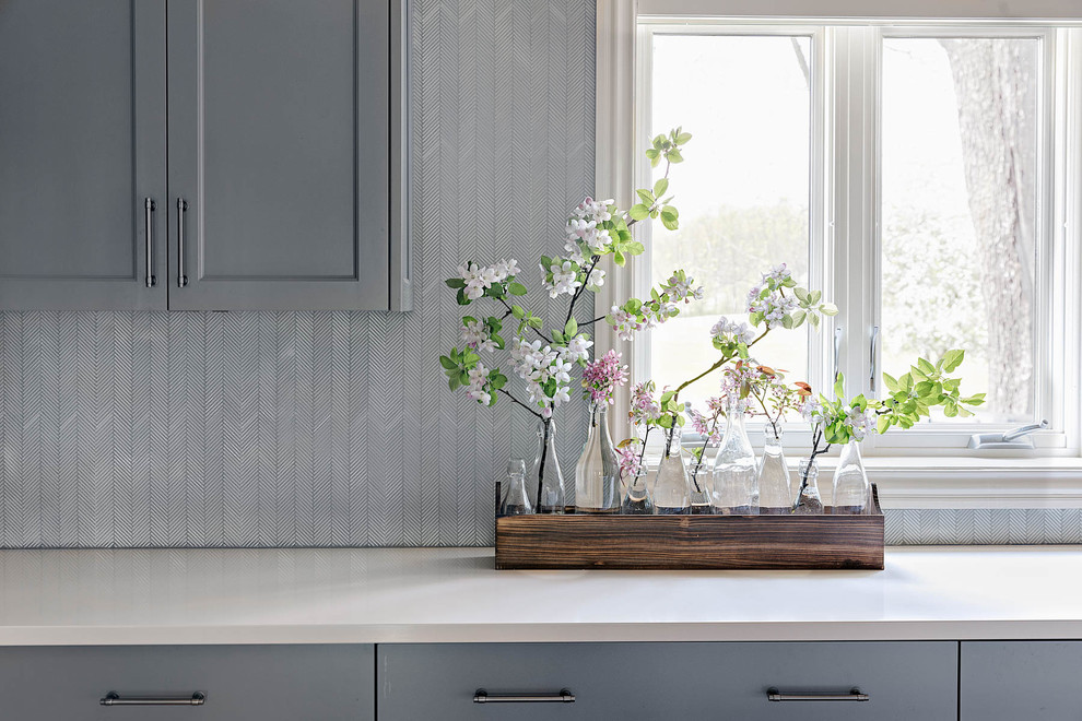 Idée de décoration pour une grande cuisine américaine minimaliste en L avec un évier de ferme, un placard avec porte à panneau encastré, un plan de travail en inox, un électroménager en acier inoxydable, parquet clair, 2 îlots, un sol marron, un plan de travail gris, des portes de placard grises et une crédence grise.