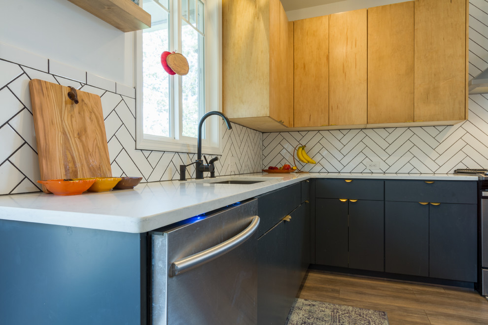 Bild på ett stort skandinaviskt kök, med en nedsänkt diskho, släta luckor, skåp i ljust trä, bänkskiva i kvartsit, vitt stänkskydd, stänkskydd i porslinskakel, rostfria vitvaror, klinkergolv i keramik, en köksö och svart golv