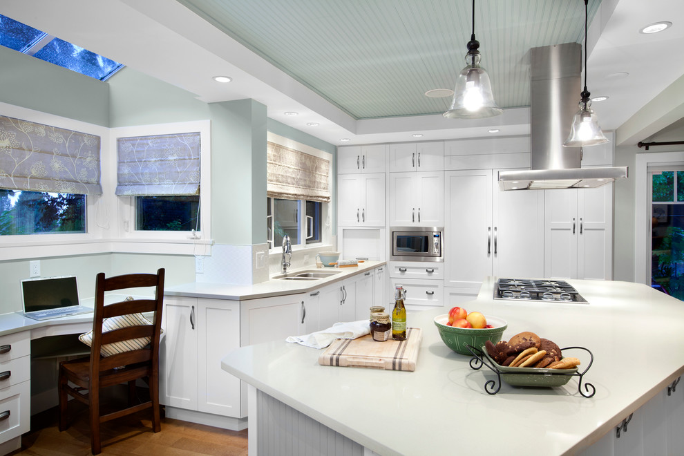 Klassisk inredning av ett kök, med en dubbel diskho, skåp i shakerstil, vita skåp, vitt stänkskydd och integrerade vitvaror