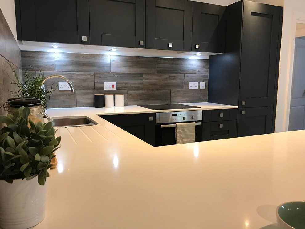 This is an example of a medium sized contemporary u-shaped open plan kitchen in Dorset with a built-in sink, shaker cabinets, quartz worktops, multi-coloured splashback, integrated appliances and a breakfast bar.