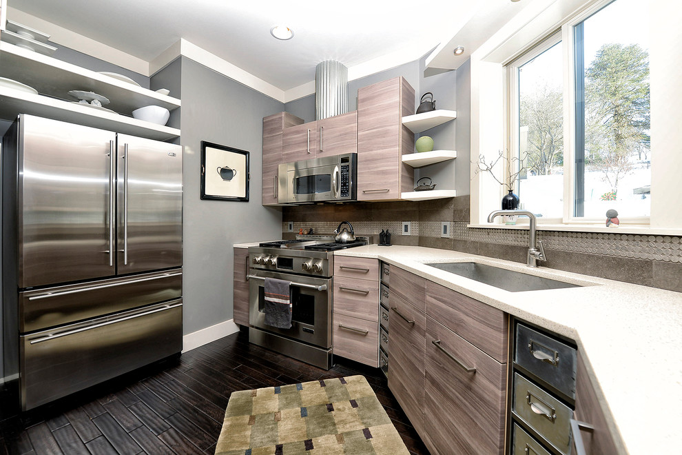 Exemple d'une cuisine tendance en L fermée avec un évier encastré, un placard à porte plane, un électroménager en acier inoxydable et un sol marron.
