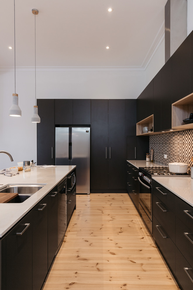 Exempel på ett modernt kök, med en dubbel diskho, släta luckor, svarta skåp, flerfärgad stänkskydd, rostfria vitvaror, ljust trägolv och en köksö