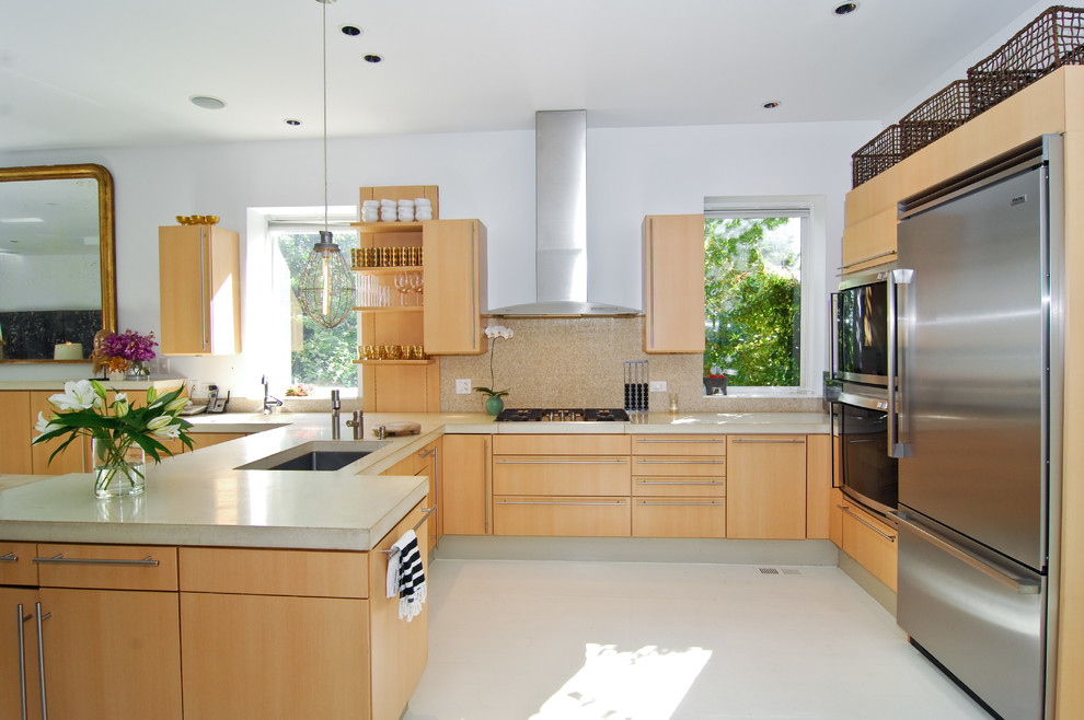 Aménagement d'une cuisine contemporaine en bois clair et U avec un placard à porte plane, une crédence beige et un électroménager en acier inoxydable.