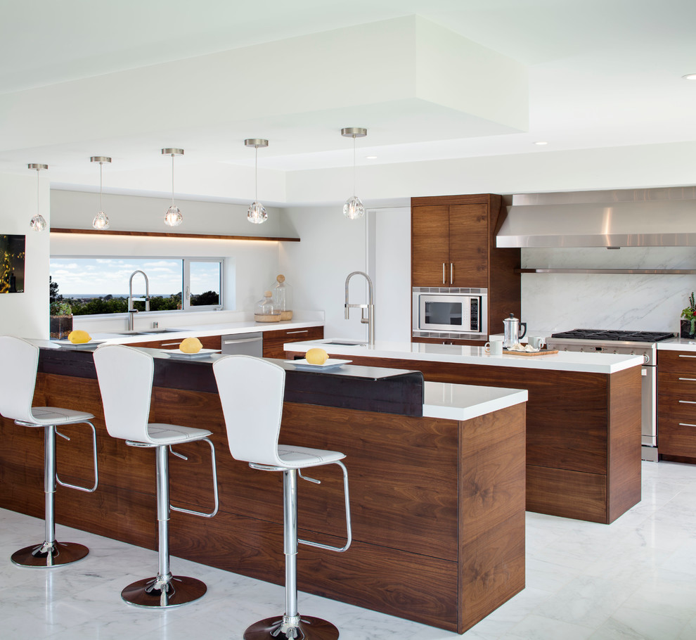 Photo of an expansive modern u-shaped open plan kitchen in San Diego with flat-panel cabinets, dark wood cabinets, white splashback, stone slab splashback, an island, a submerged sink, stainless steel appliances, marble flooring and grey floors.