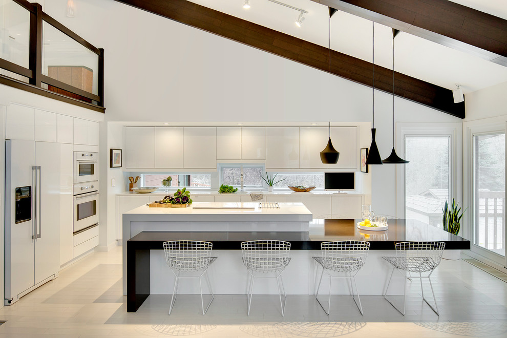 Bild på ett stort skandinaviskt kök, med en undermonterad diskho, släta luckor, vita skåp, bänkskiva i kvarts, vitt stänkskydd, vita vitvaror, ljust trägolv och en köksö