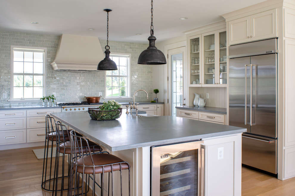 Example of a large farmhouse light wood floor and beige floor eat-in kitchen design in DC Metro with a farmhouse sink, concrete countertops, blue backsplash, glass tile backsplash, an island, gray countertops, recessed-panel cabinets, beige cabinets and stainless steel appliances