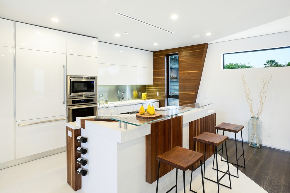 Inspiration for a contemporary single-wall kitchen in Los Angeles with flat-panel cabinets, white cabinets, metallic splashback, metal splashback, stainless steel appliances, dark hardwood flooring and an island.