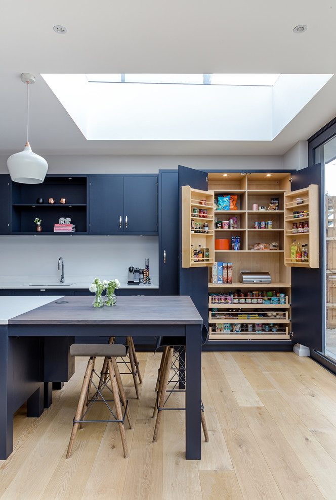 Diseño de cocina clásica renovada grande con fregadero de un seno, encimera de vidrio, suelo de madera en tonos medios, suelo marrón, puertas de armario azules, salpicadero blanco, una isla, armarios con paneles lisos y encimeras azules