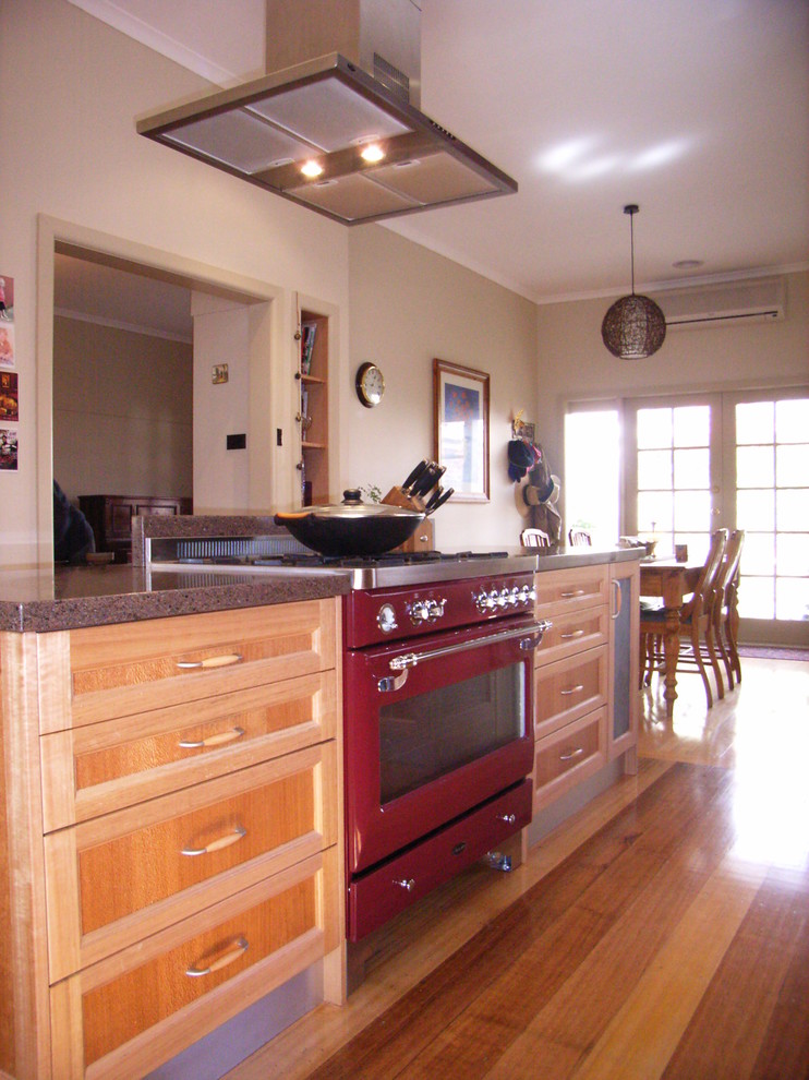 Exempel på ett mellanstort modernt kök, med en nedsänkt diskho, skåp i shakerstil, skåp i ljust trä, bänkskiva i kvarts, rött stänkskydd, glaspanel som stänkskydd, färgglada vitvaror, ljust trägolv och en köksö