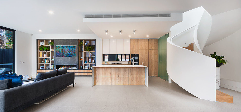 Offene Moderne Küche in L-Form mit flächenbündigen Schrankfronten, hellbraunen Holzschränken, schwarzen Elektrogeräten, Kücheninsel, grauem Boden und weißer Arbeitsplatte in Melbourne
