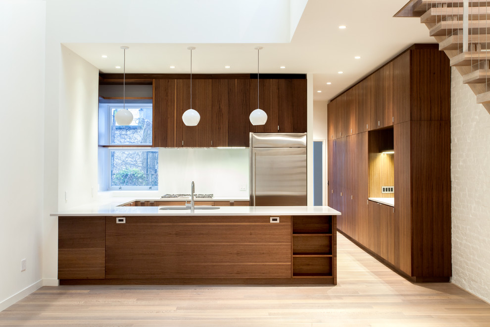 Mittelgroße Moderne Küche in L-Form mit flächenbündigen Schrankfronten, dunklen Holzschränken, braunem Holzboden, Küchengeräten aus Edelstahl und Halbinsel in New York