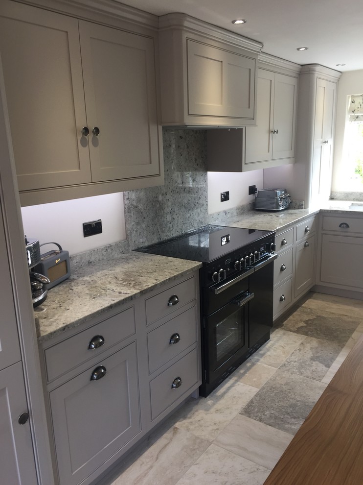 Design ideas for a medium sized traditional l-shaped kitchen/diner in Cheshire with a double-bowl sink, shaker cabinets, grey cabinets, granite worktops, grey splashback, stone slab splashback, black appliances, ceramic flooring and an island.