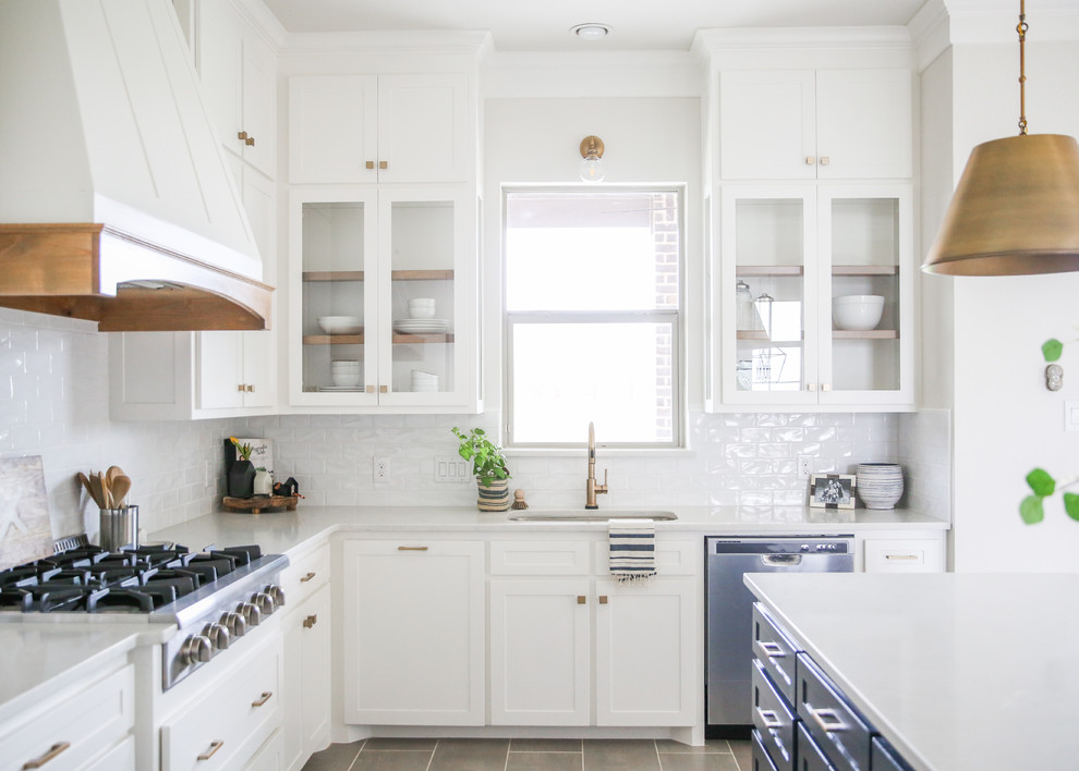 This is an example of a medium sized classic l-shaped open plan kitchen in Dallas with a submerged sink, shaker cabinets, white cabinets, quartz worktops, white splashback, ceramic splashback, stainless steel appliances, porcelain flooring, an island, grey floors and white worktops.
