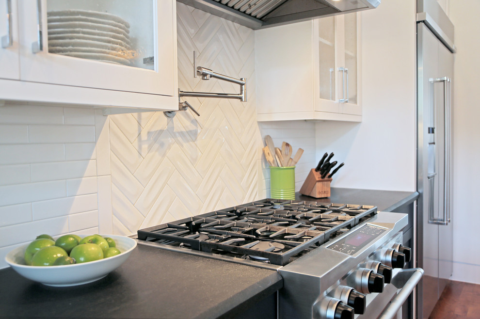 Bild på ett mellanstort funkis grå grått kök, med luckor med glaspanel, vita skåp, bänkskiva i kvarts, vitt stänkskydd, stänkskydd i tunnelbanekakel, rostfria vitvaror, mellanmörkt trägolv, en köksö och brunt golv