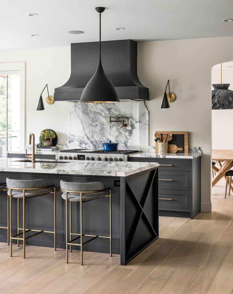 Large classic u-shaped kitchen/diner in Vancouver with a submerged sink, recessed-panel cabinets, grey cabinets, marble worktops, white splashback, granite splashback, black appliances, light hardwood flooring, an island, brown floors and white worktops.