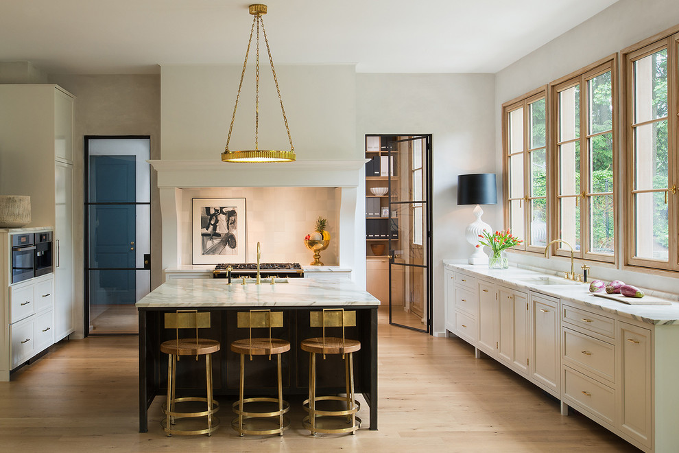 Transitional u-shaped light wood floor enclosed kitchen photo in DC Metro with an undermount sink, recessed-panel cabinets, white cabinets, marble countertops and an island