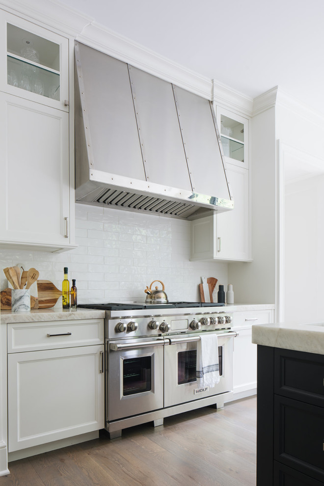 Klassische Wohnküche mit weißen Schränken, Küchenrückwand in Weiß, Rückwand aus Keramikfliesen, Küchengeräten aus Edelstahl und Kücheninsel in Chicago