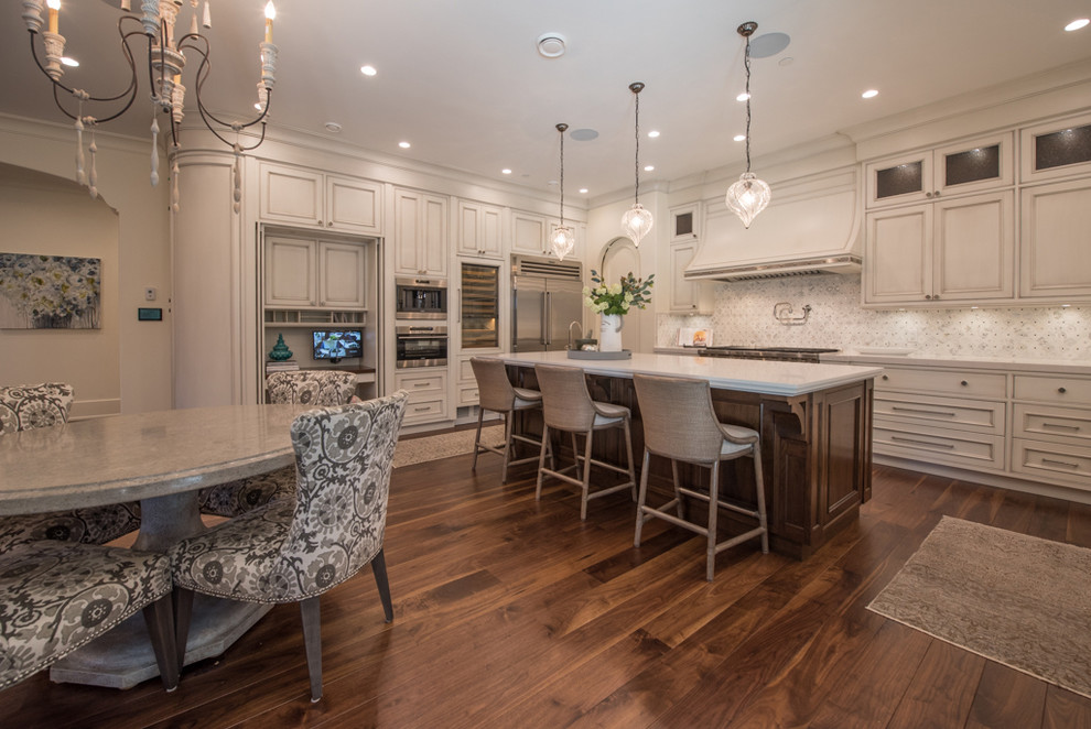 Huge tuscan u-shaped medium tone wood floor eat-in kitchen photo in Vancouver with an undermount sink, recessed-panel cabinets, distressed cabinets, limestone countertops, multicolored backsplash, ceramic backsplash, stainless steel appliances and an island
