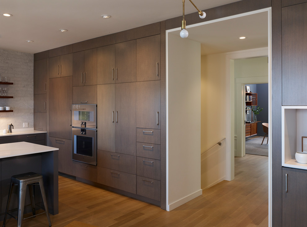 Photo of a small contemporary u-shaped open plan kitchen in San Francisco with a double-bowl sink, flat-panel cabinets, dark wood cabinets, quartz worktops, grey splashback, stone tiled splashback, stainless steel appliances, medium hardwood flooring and a breakfast bar.