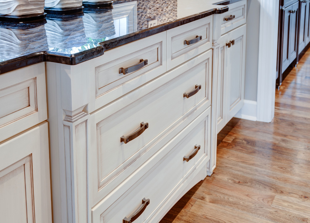 Example of a mid-sized arts and crafts galley medium tone wood floor kitchen design in Chicago with an undermount sink, flat-panel cabinets, white cabinets, granite countertops, brown backsplash, stainless steel appliances and an island