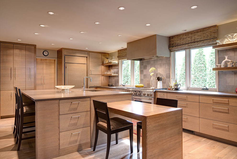 Cette image montre une cuisine encastrable design en bois clair avec un évier encastré, un placard à porte plane, une crédence grise, parquet clair et 2 îlots.