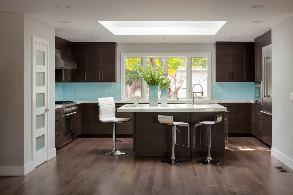 Inspiration for a contemporary u-shaped medium tone wood floor kitchen remodel in San Francisco with flat-panel cabinets, dark wood cabinets, blue backsplash, glass sheet backsplash, stainless steel appliances and an island