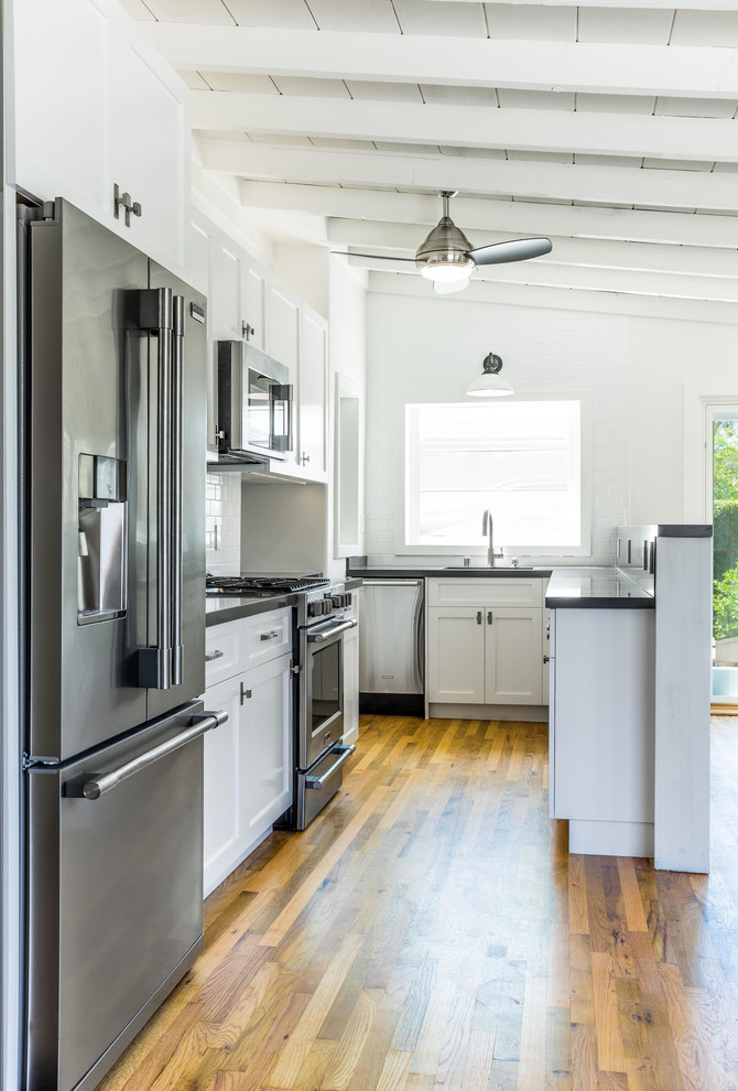 Small transitional u-shaped medium tone wood floor and brown floor kitchen photo in Orange County with an undermount sink, shaker cabinets, white cabinets, quartzite countertops, white backsplash, ceramic backsplash, stainless steel appliances and no island
