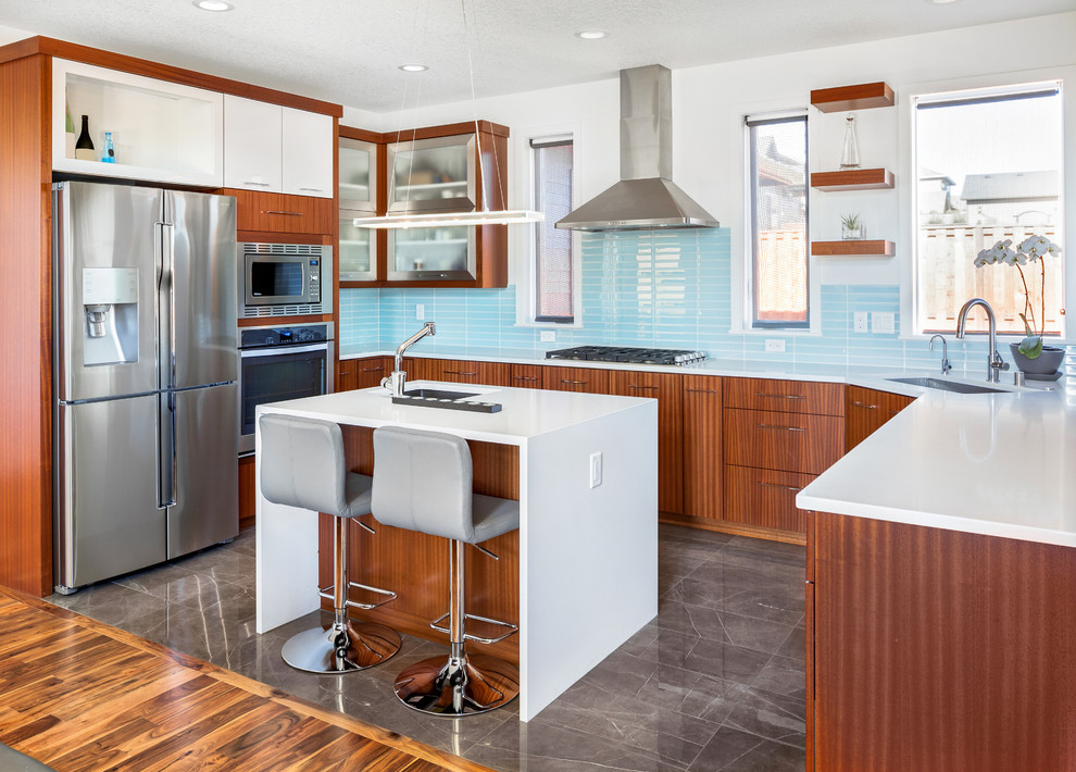 Inredning av ett modernt mellanstort vit vitt kök, med blått stänkskydd, en köksö, en undermonterad diskho, släta luckor, skåp i mellenmörkt trä, bänkskiva i koppar, stänkskydd i keramik, rostfria vitvaror, marmorgolv och grått golv