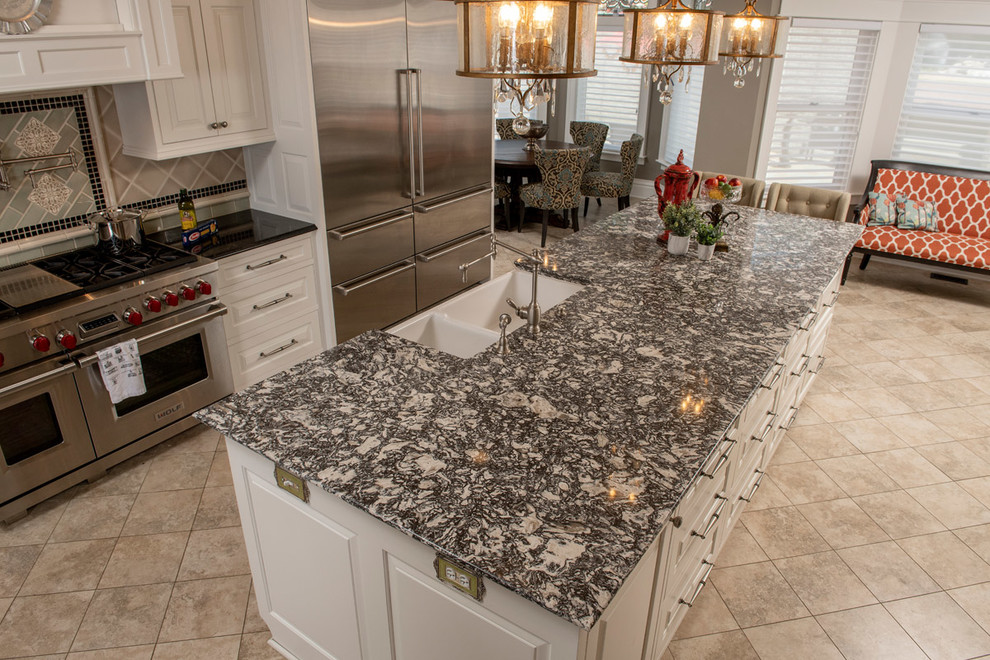Example of a large ornate single-wall porcelain tile and gray floor open concept kitchen design in Other with an undermount sink, raised-panel cabinets, white cabinets, quartzite countertops, brown backsplash, porcelain backsplash, stainless steel appliances, an island and gray countertops