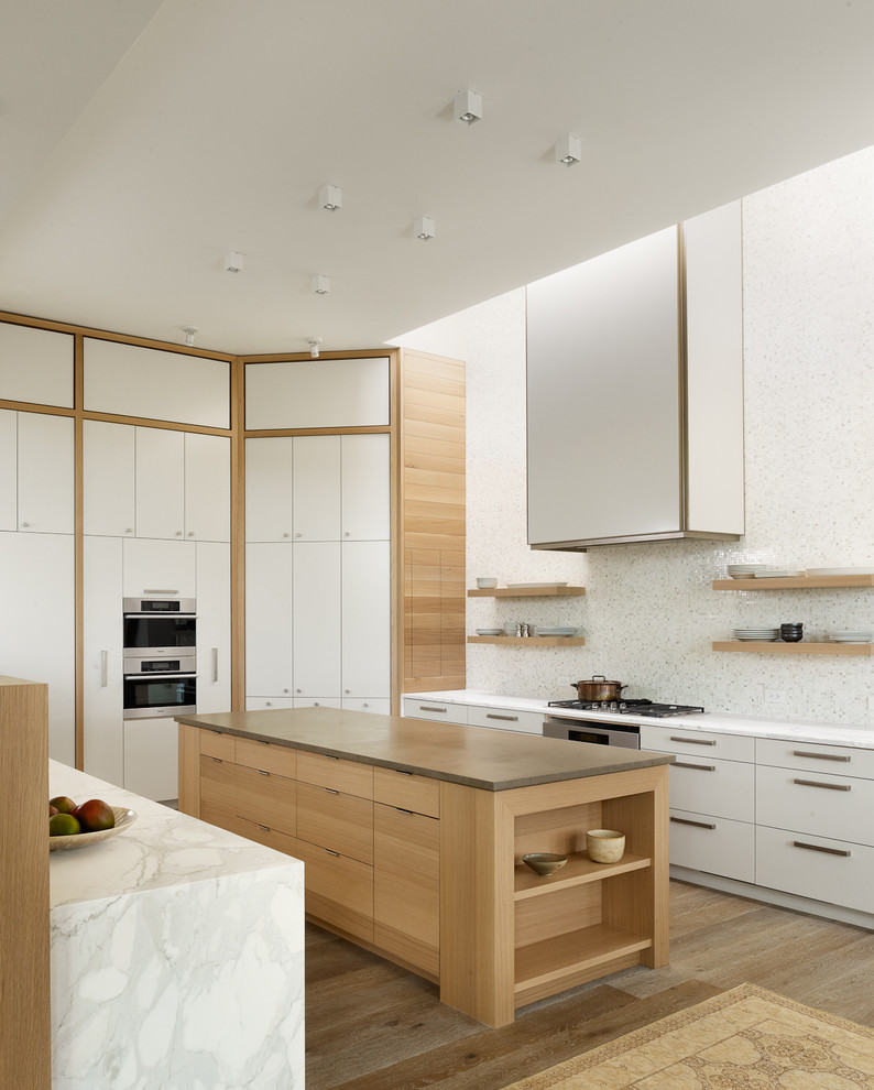 Diseño de cocina actual con armarios con paneles lisos, puertas de armario blancas, salpicadero blanco y electrodomésticos de acero inoxidable