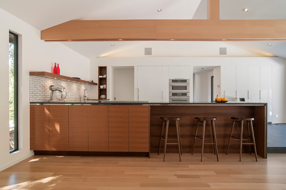 Photo of a contemporary kitchen in San Francisco with flat-panel cabinets, white cabinets, integrated appliances, white splashback and metro tiled splashback.