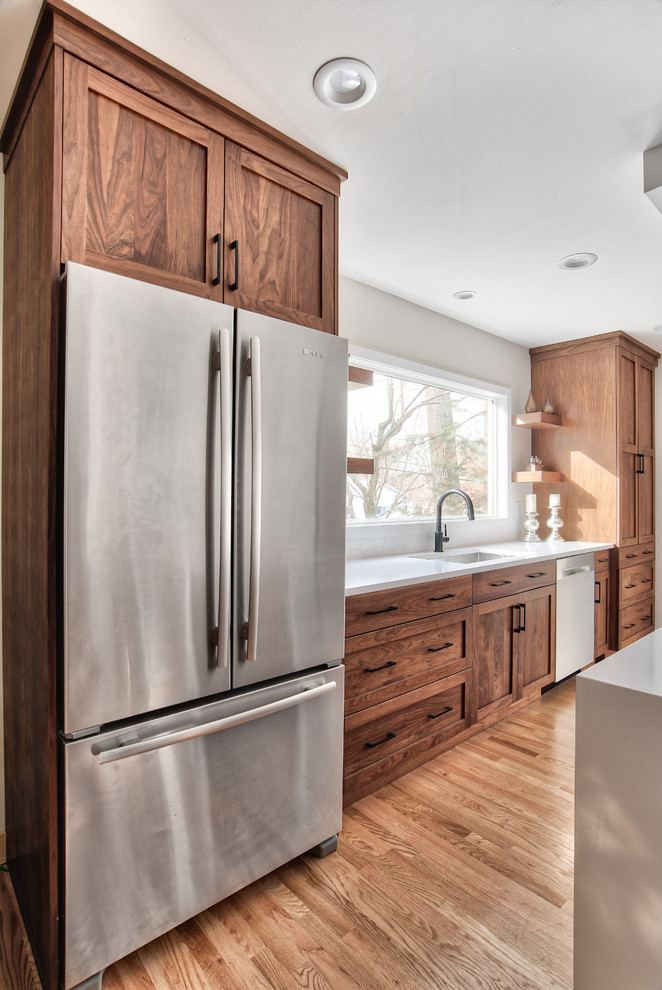 Example of a mid-sized minimalist single-wall eat-in kitchen design in New York with an undermount sink, shaker cabinets, medium tone wood cabinets, quartzite countertops, white backsplash, stainless steel appliances, an island and white countertops