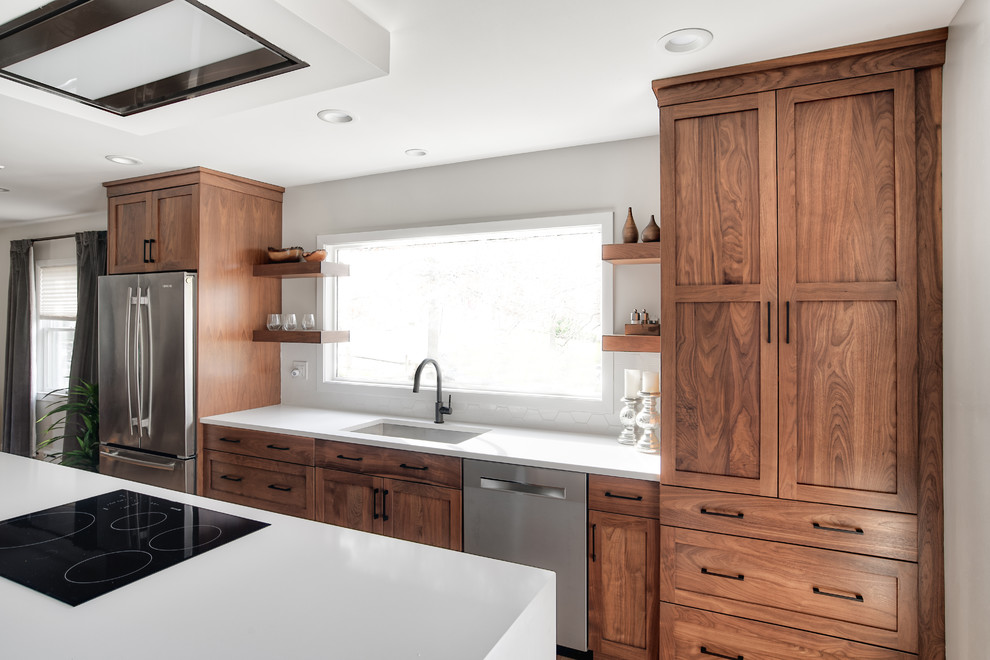 Foto på ett mellanstort funkis vit linjärt kök och matrum, med en undermonterad diskho, skåp i shakerstil, skåp i mellenmörkt trä, bänkskiva i kvartsit, vitt stänkskydd, rostfria vitvaror och en köksö