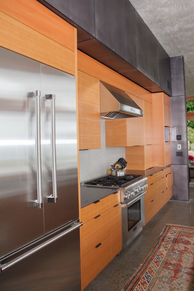 This is an example of a contemporary kitchen in Seattle with flat-panel cabinets, medium wood cabinets, engineered stone countertops and stainless steel appliances.