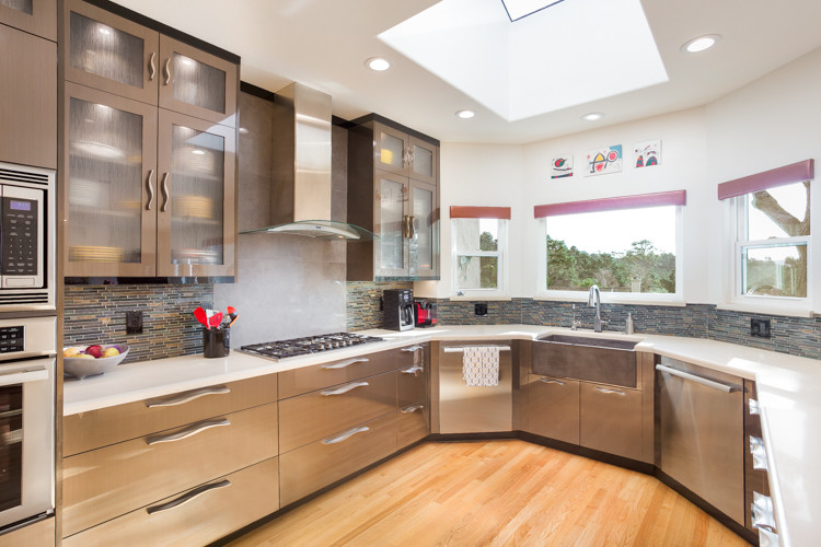 Medium sized modern u-shaped kitchen/diner in Other with a belfast sink, flat-panel cabinets, brown cabinets, engineered stone countertops, multi-coloured splashback, mosaic tiled splashback, stainless steel appliances and light hardwood flooring.