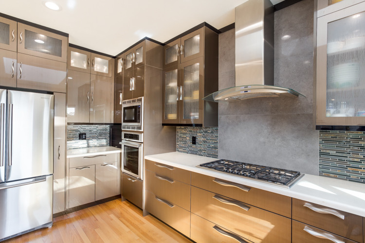 Medium sized modern u-shaped kitchen/diner in Other with a belfast sink, flat-panel cabinets, brown cabinets, engineered stone countertops, multi-coloured splashback, mosaic tiled splashback, stainless steel appliances and light hardwood flooring.